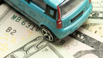 A turquoise car sitting on several twenty dollar bills