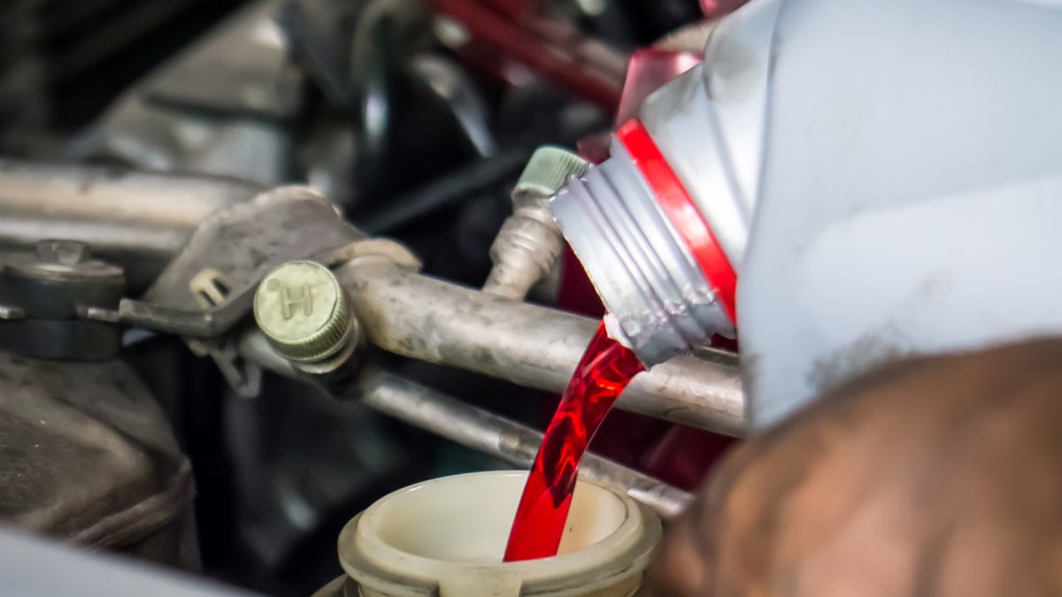 A technician pouring transmission fluid.