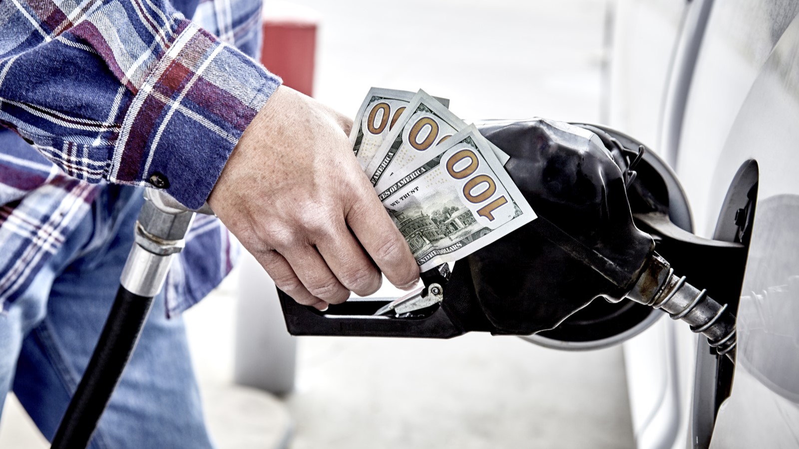 A customer refills gas in a car while holding money