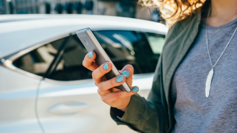 A car owner uses a smartphone app to unlock their car