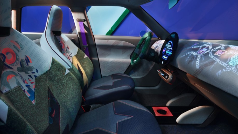 The cabin of the Mini Aceman concept. Its seats are upholstered in many fabrics cut at odd angles,including one in blue denim and one with neon X's and O's. The dashboard has moving multicolored words projected onto it.