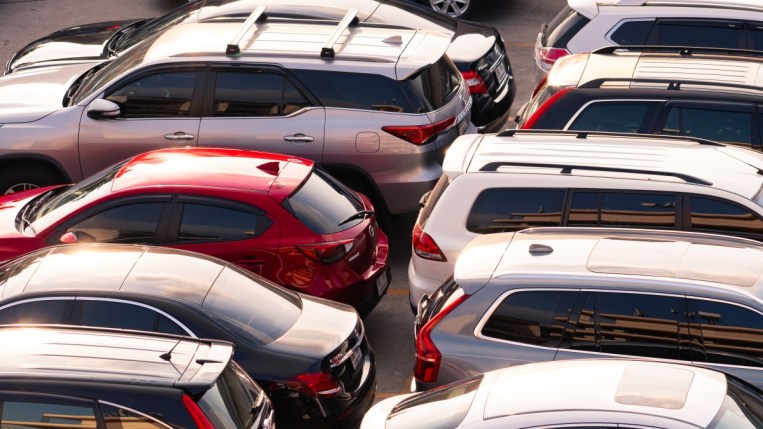 Used cars sit for sale at a dealership. We see them lined up back-to-back, of many makes and models.
