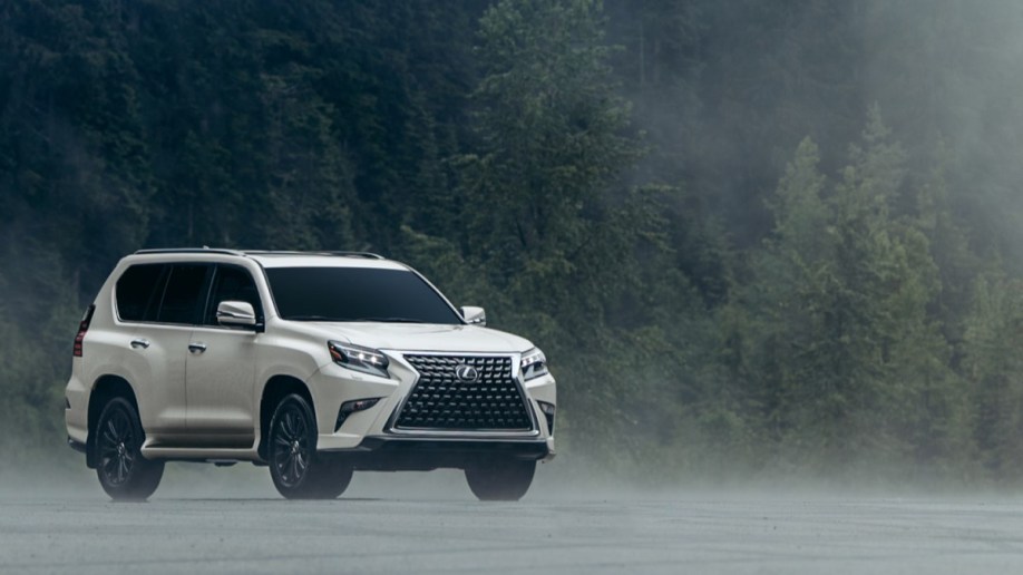 The 2023 Lexus GX sits in front of an evergreen forest in fog. The SUV is white. We see it from a front quarter angle, facing slightly to our right.