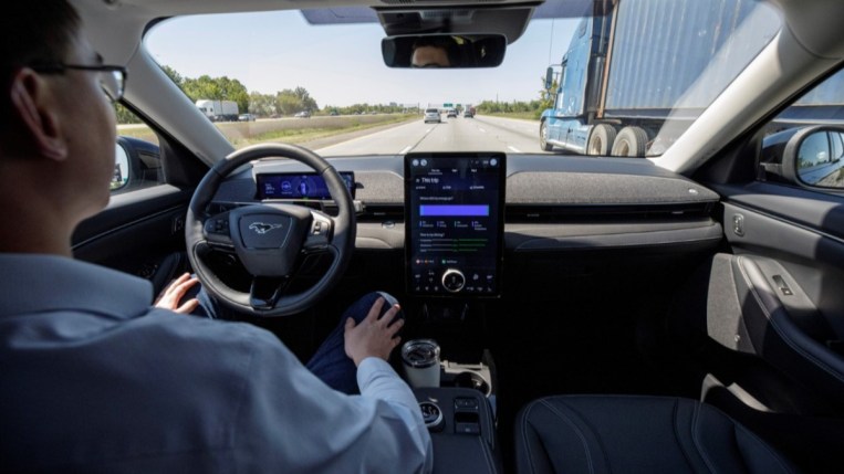 A driver demonstrates Ford's Blue Cruise system with their hands off the wheel in traffic