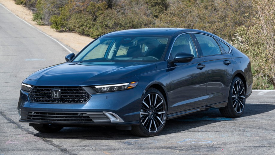 Blue 2023 Honda Accord Hybrid near bushes.