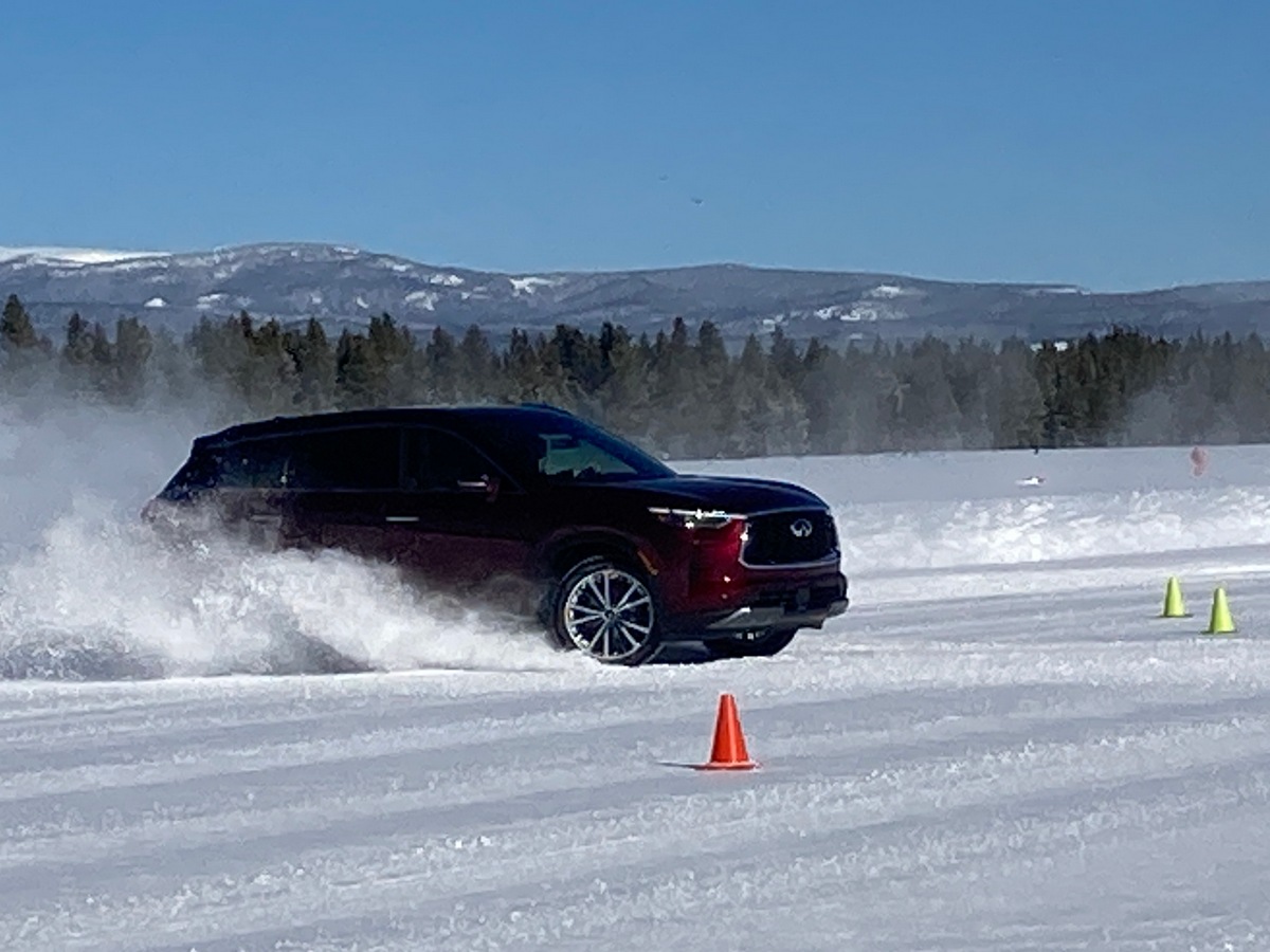 Burgundy 2023 Infiniti QX60 driving in snow.