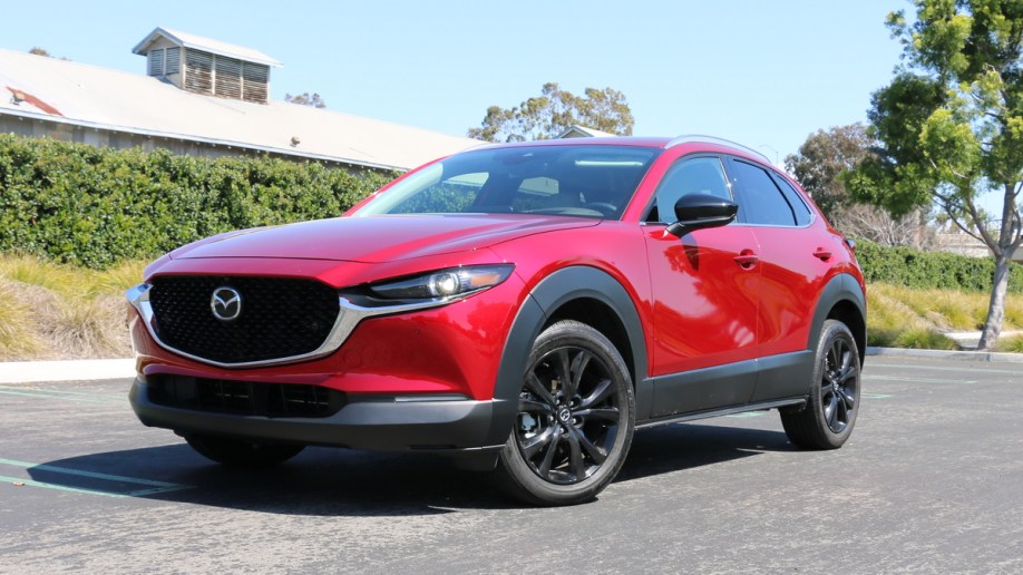Red 2023 Mazda CX-30 with green hedge in the background.