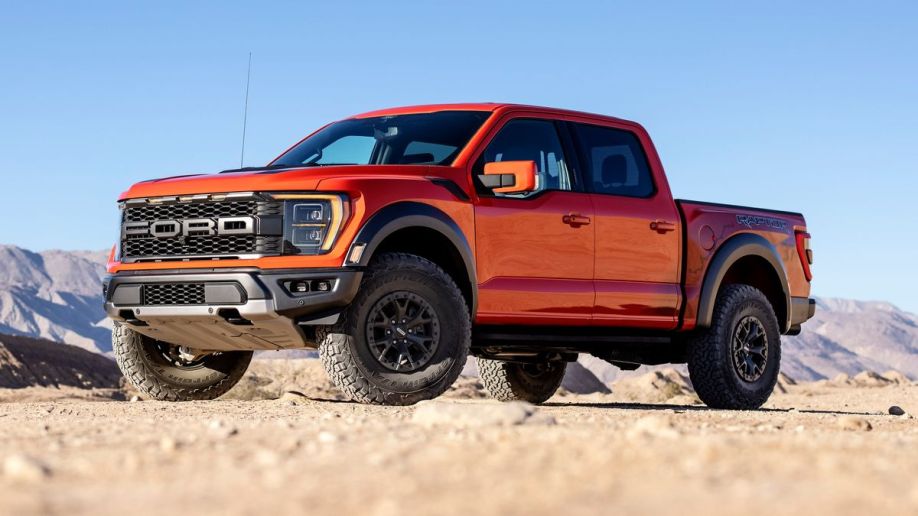 2023 Ford F-150 Raptor in orange with hills in the background.