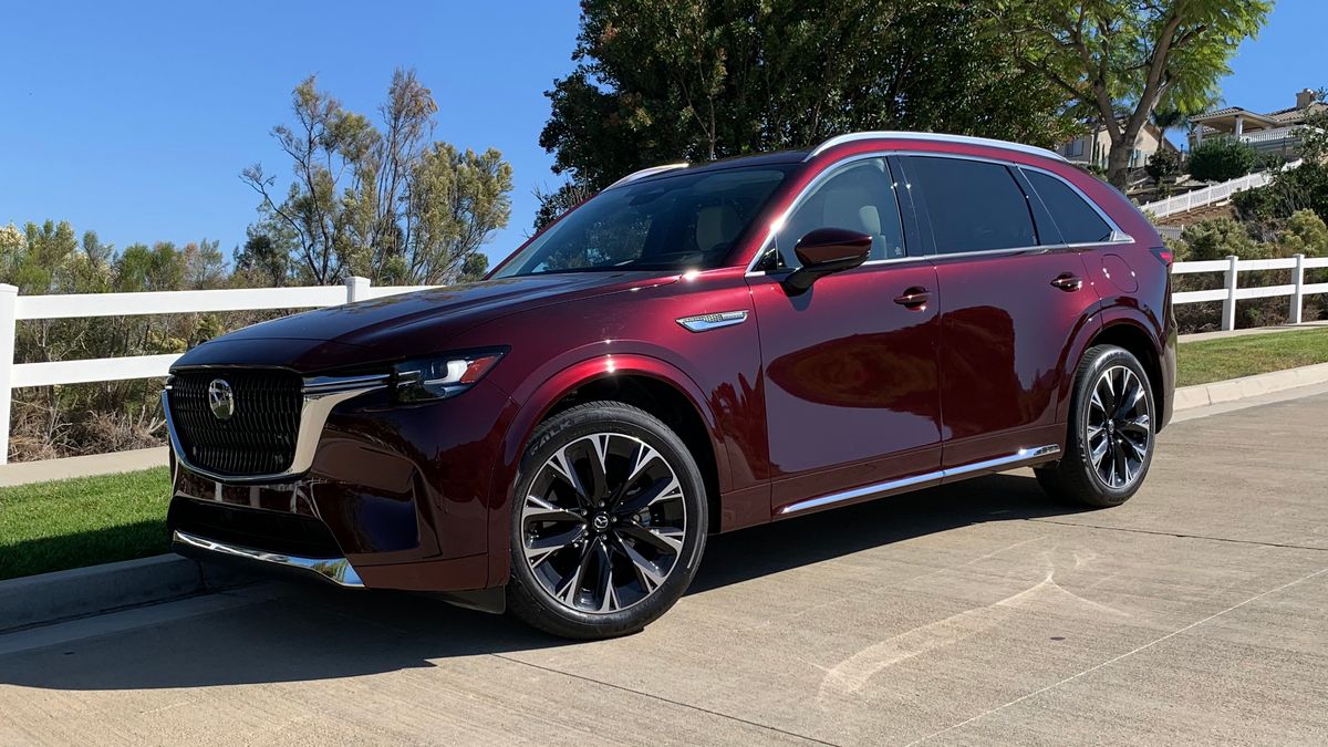 2024 Mazda CX-90 Turbo in Artisan Red near a white fence.