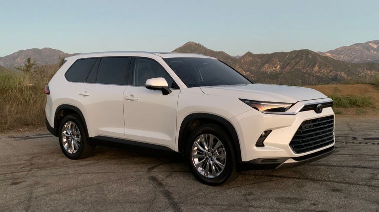 2024 Toyota Grand Highlander in white with mountains in the background.