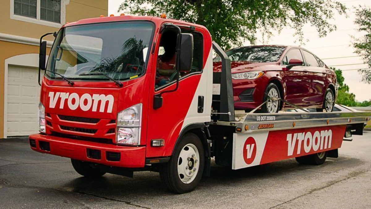 A Vroom truck delivering a sedan