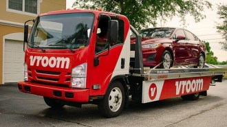 A Vroom truck delivering a sedan
