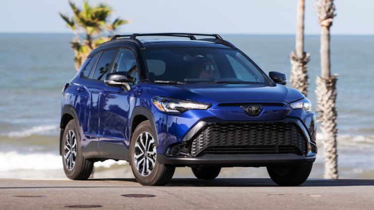 2024 Toyota Corolla Cross Hybrid SE in Blue Crush Metallic with the ocean in the background.
