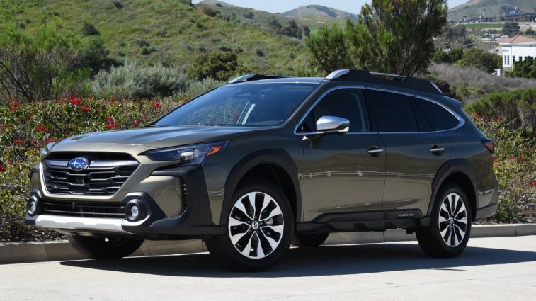 2024 Subaru Outback Touring with green hills in the background.