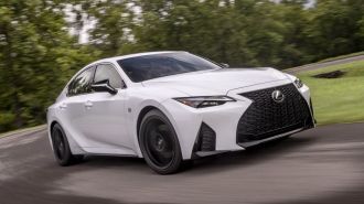 2024 Lexus IS 350 F-Sport in white driving around a corner.