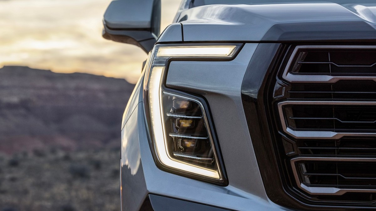 A teaser photo showing one headlight of the 2025 GMC Yukon