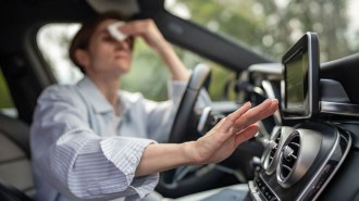 A person wiping forehead while adjusting car AC vent.