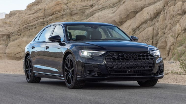 2024 Audi A8 in Firmament Blue parked on a highway near rock formations.
