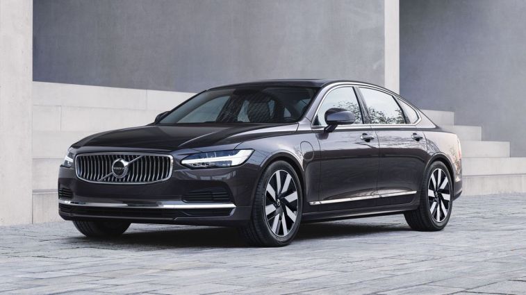 2024 Volvo S90 Recharge T8 AWD in Platinum Grey parked in front of a building.