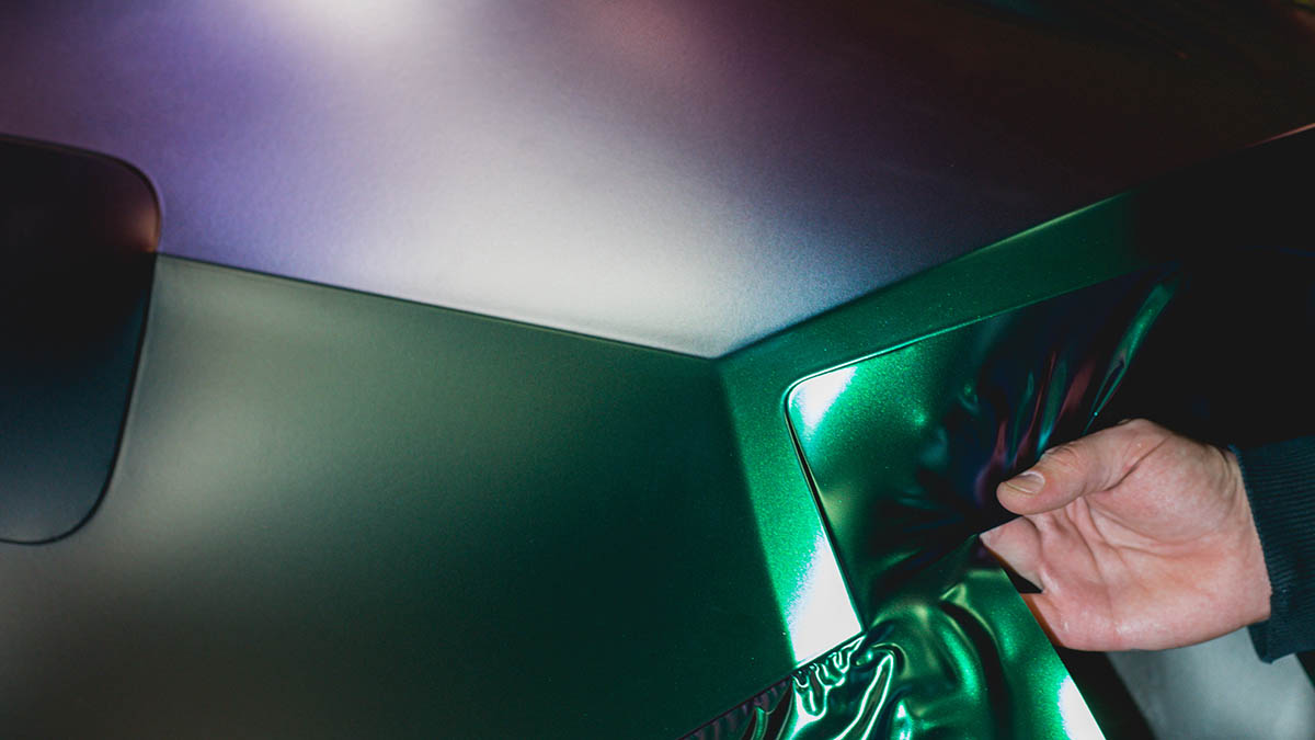 A technician installing green vinyl car wrap.