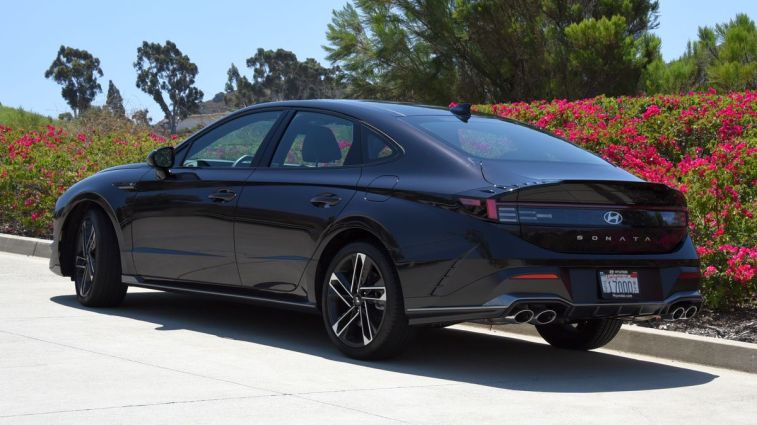 2024 Hyundai Sonata N Line in Carbon Blue with trees and bougainvillea in the background.