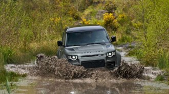 The 2025 Defender Octa seen from a front quarter angle, fording water