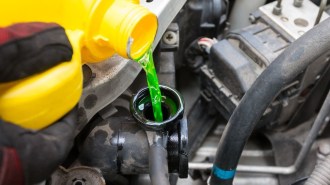 A technician pouring engine coolant.